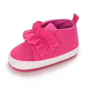Nahaufnahme von pinkfarbenen Baby-Lauflernschuhen mit Rüschendetails und weicher Sohle.