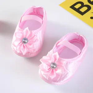 Nahaufnahme von rosa Baby-Prinzessin-Schuhen aus Satin mit Schleifenblumen und Strasssteinen