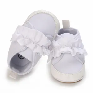 Detaillierte Ansicht weißer Babylauflernschuhe mit Rüschendekor und weicher Sohle
