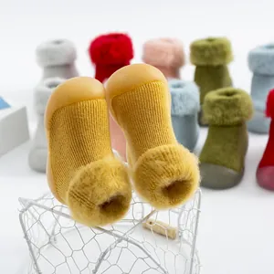 Detalle de zapatos tipo calcetín amarillos para bebé con pelo suave y suela.