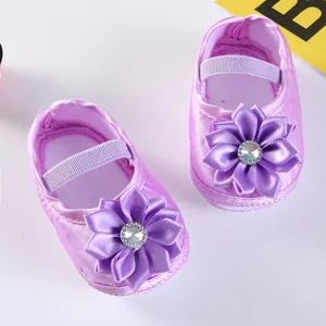 Nahaufnahme lila Baby-Prinzessin-Schuhe mit großer Satinblume und Strass-Detail