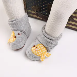 Détail de chaussons de marche gris pour bébé avec une broderie d'oiseau jaune mignon