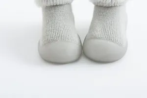 Primer plano de zapatos calcetín gris para bebé con forro cálido y suela blanda.