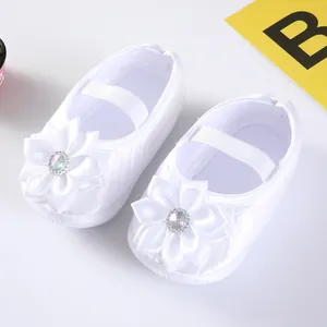 Detailansicht weißer Satin-Babyschuhe mit eleganten Blumen- und Kristallverzierungen