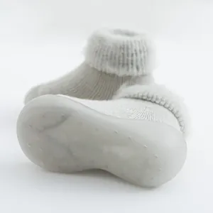 Primer plano de un zapato calcetín gris para bebé con suela antideslizante