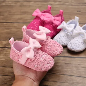 Detailansicht der rosa Häkel-Prinzessinnenschuhe für Babys mit Schleife auf einer Hand