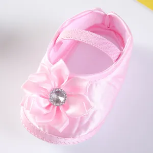 Detaillierte Makroaufnahme eines rosa Baby-Prinzessinenschuhs aus Satin mit Blume.