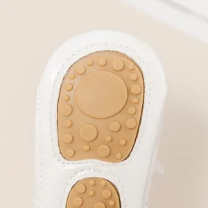 Primer plano de la suela de goma antideslizante de zapatos de bebé princesa blancos.