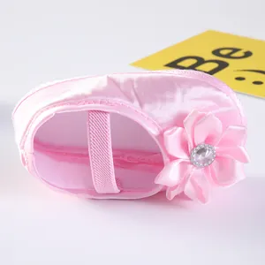 Detailansicht eines weichen rosa Satin-Babyschuhs mit einer dekorativen Stoffblume darauf
