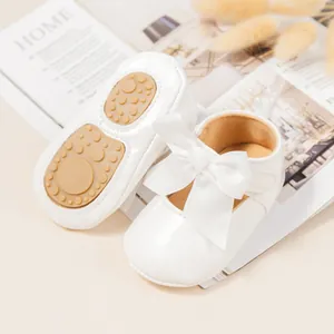 Primer plano de zapatos blancos de princesa para bebé con lazo y suela antideslizante
