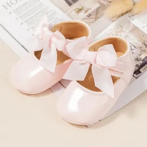 Primer plano de zapatos de princesa para bebé en charol rosa con un lazo grande
