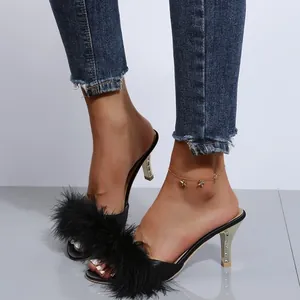 Nahaufnahme von modischen schwarzen Stilettosandalen mit Kunstfell und engen Jeans