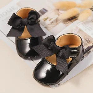 Primer plano de zapatos de charol negro para bebé con elegantes lazos de cinta