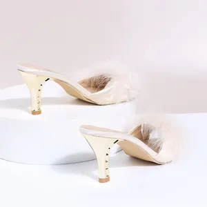 Detail von eleganten beigen Stöckelsandalen mit weichen, flauschigen Federriemen
