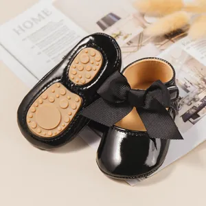 Primer plano de zapatos de bebé con suelas suaves antideslizantes y lazos negros