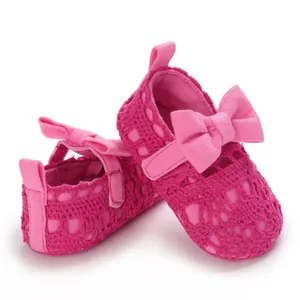 Makroaufnahme von leuchtend pinken gehäkelten Baby-Prinzessin-Schuhen mit Schleife