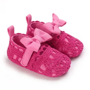Nahaufnahme von pinkfarbenen gestrickten Baby-Prinzessin-Schuhen mit dekorativen Schleifen.