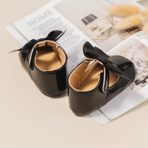 Vista trasera de zapatos de charol negro para bebé con elegantes lazos decorativos
