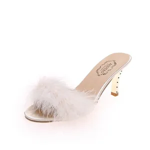 Detailansicht der weißen Pelzriemen und des goldenen Stiletto-Absatzes