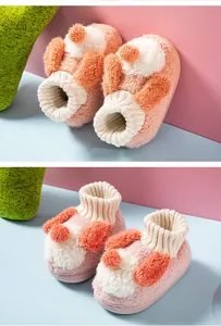 Close-up view of cute plush toddler slippers with furry texture and knitted cuffs.