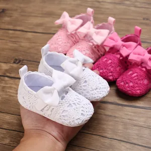 Detaillierte Nahaufnahme von weichen gehäkelten Baby-Prinzessinnenschuhen in Weiß und Rosa