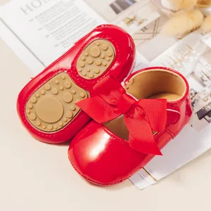 Primer plano de zapatos de bebé en charol rojo con lazo grande y suela antideslizante