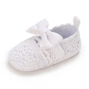 Detailansicht der weißen Häkelspitzen-Babyschuhe für Mädchen mit großer Dekoschleife