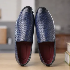 Stylish men's blue slip-on loafers featuring woven leather texture on a wooden desk