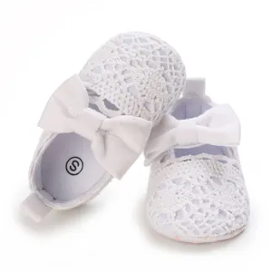 Detailansicht der weißen Spitzen-Babyschuhe mit einem eleganten großen Schleifendesign.
