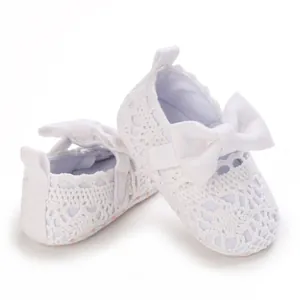 Nahaufnahme weißer Baby-Prinzessinenschuhe mit zarter Spitze und eleganter Schleife.