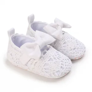 Nahaufnahme von weißen, gehäkelten Baby-Prinzessin-Schuhen mit dekorativen Schleifen