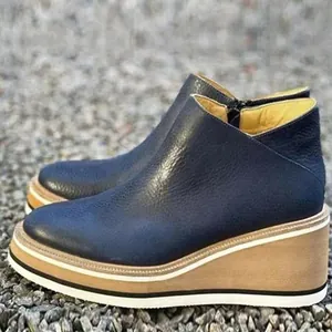 Detailed view of navy blue pebbled leather wedge platform ankle boots with side zipper.