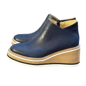 Detailed side view of navy blue pebbled leather ankle boots featuring wood wedge heels