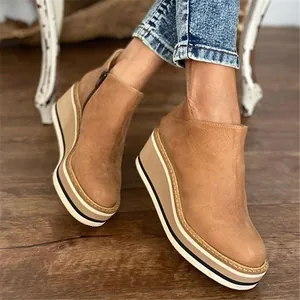 Close-up of brown suede wedge ankle boots with thick striped platform and side zipper.