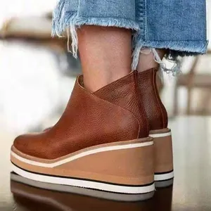 Close-up of retro brown leather wedge ankle boots with thick platform and side zipper