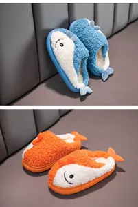 Dettaglio di pantofole di peluche a forma di pesce per bambini, blu e arancione caldo.