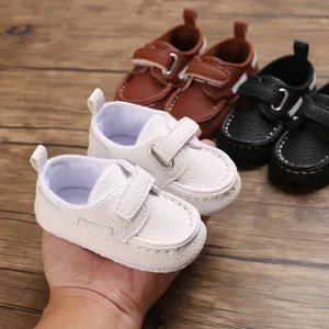 Nahaufnahme von weißen Baby-Lederschuhen mit weicher Sohle in der Hand zum Größenvergleich