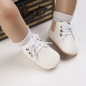 Vista macro detallada de zapatos de suela blanda para bebé en cuero sintético blanco con cordones