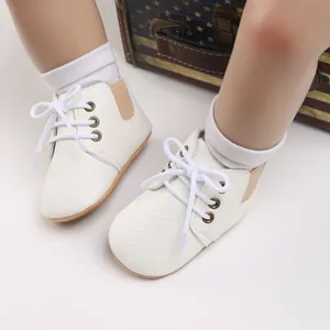 Detalle de zapatos de marcha suaves para bebé en blanco con cordones y tonos marrones