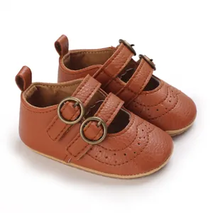 Detailed macro view of brown baby Mary Jane shoes with double buckles and soft soles.
