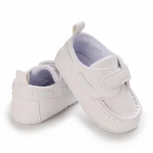 Nahaufnahme von weißen Baby-Mokassins aus Leder mit weicher Sohle und Klettverschluss