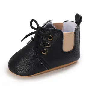 Zapato de bebé negro con suela blanda, lateral elástico y cordones