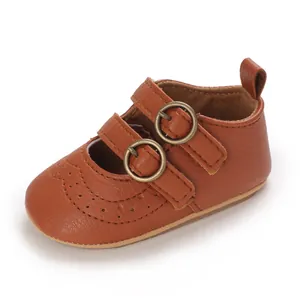 Close-up of brown faux leather baby shoe with double buckles and wingtip details