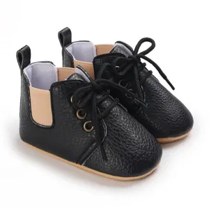Primer plano de zapatos de gateo para bebé en cuero sintético negro con elásticos beige