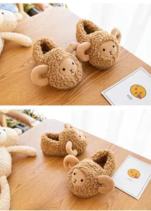 Macro view of cute brown sheep-shaped plush slippers for toddlers on a wooden table.