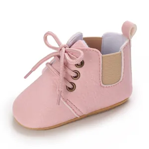 Primer plano de zapatos rosas de suela blanda para bebés con cordones y detalle elástico