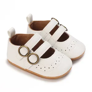 Detail of white baby Mary Jane shoes with bronze buckles and brogue texture