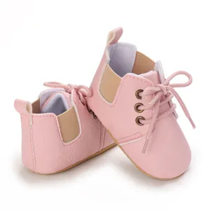 Detalle de zapatos de bebé rosa con cordones y suela blanda para primeros pasos cómodos.