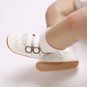 Detailed side view of white soft-sole baby walking shoes featuring elegant gold buckles