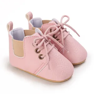 Detalle de los zapatos de bebé rosa con suela blanda y cierre de cordones para bebés